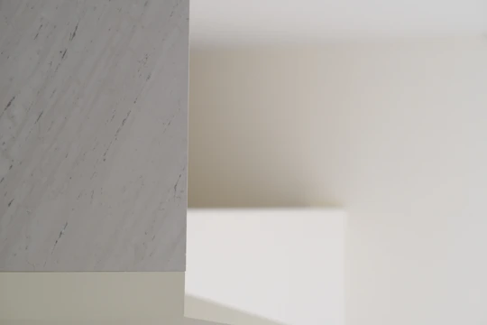 Close-up of polished white marble floor tiles reflecting soft natural light in a minimalist room.