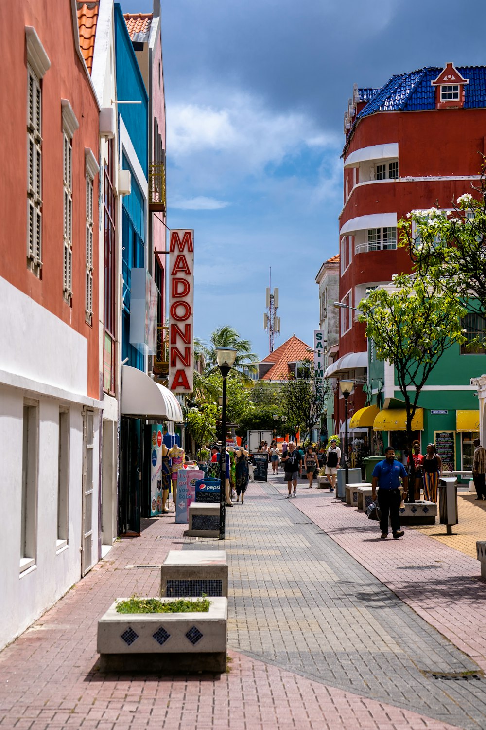 a city street with people walking and sitting on benches