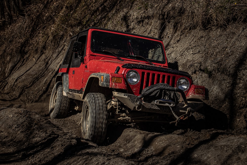 a red jeep driving on a rocky road