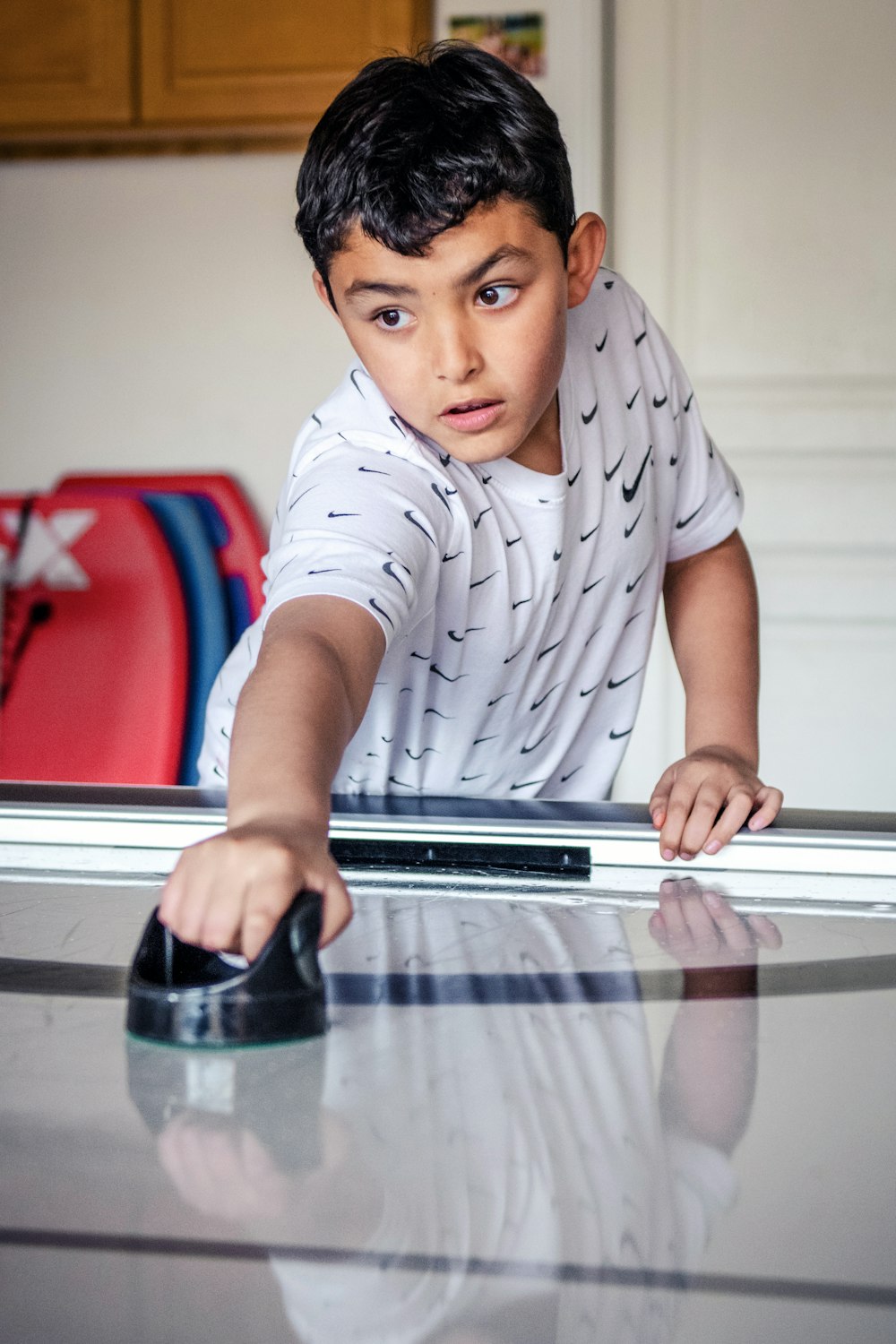 a young boy leaning over a table with a mouse