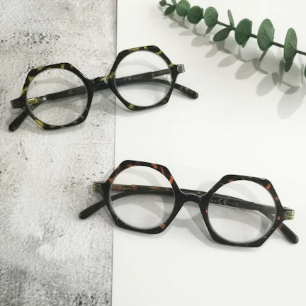 Close-up of a bold, twisted vine patterned eyeglass frame resting on a wooden table.