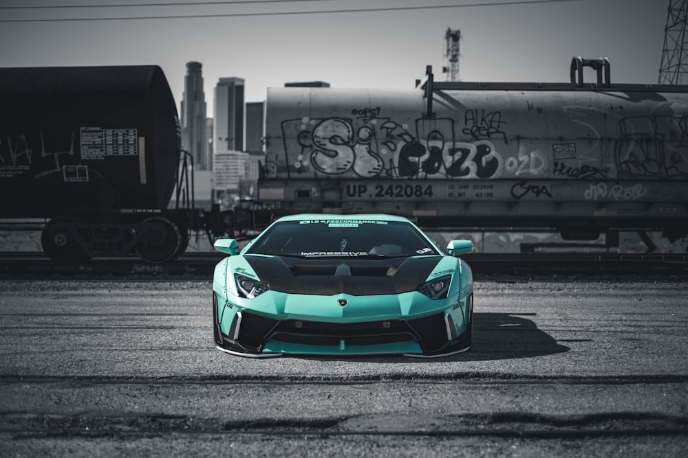 a blue sports car parked in front of a train
