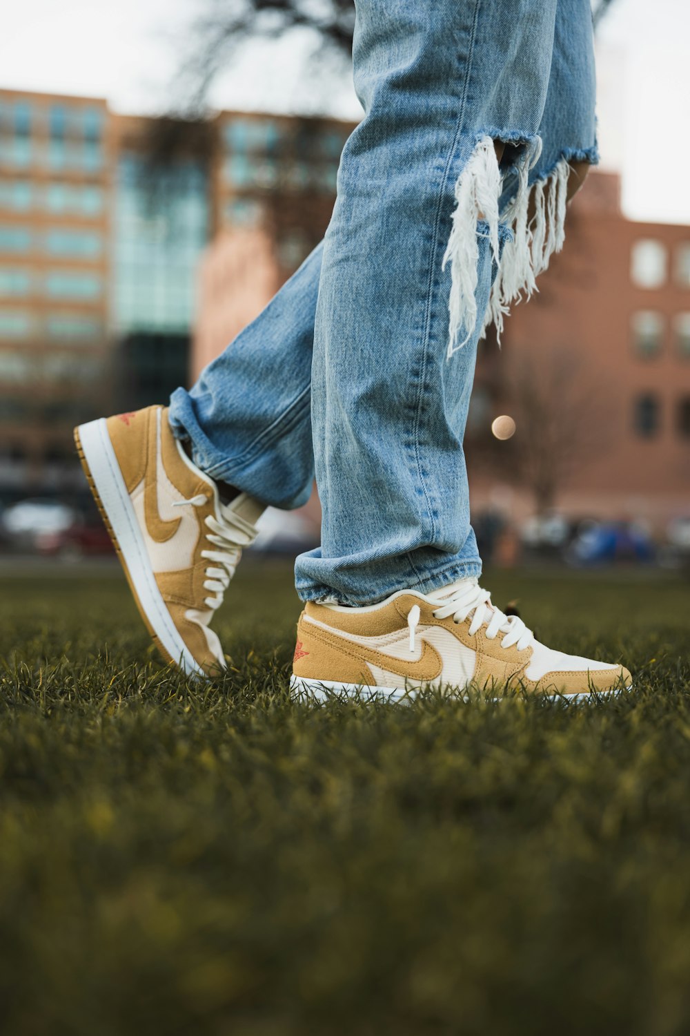 a person with ripped jeans and sneakers standing in the grass