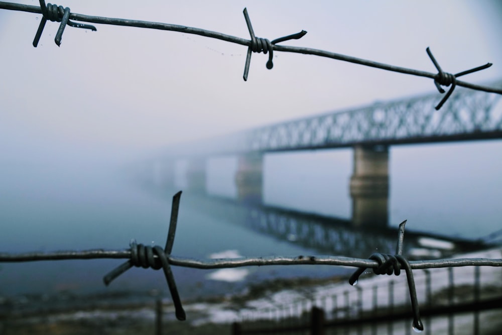 a view of a bridge from behind a barbed wire fence