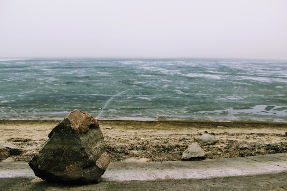 a large rock sitting on top of a sandy beach