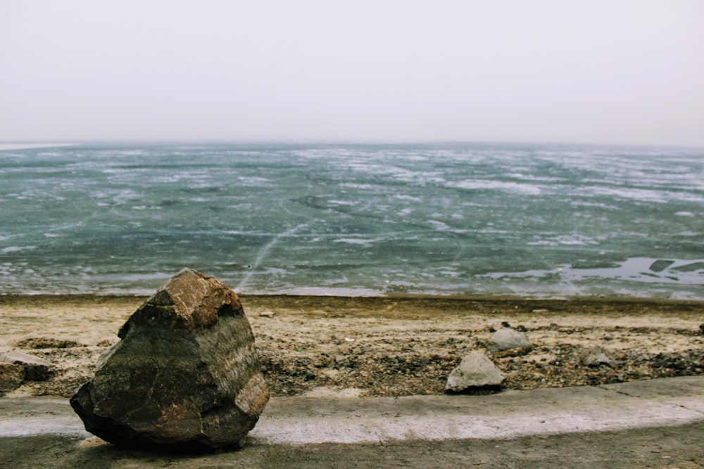 una grande roccia seduta sulla cima di una spiaggia sabbiosa