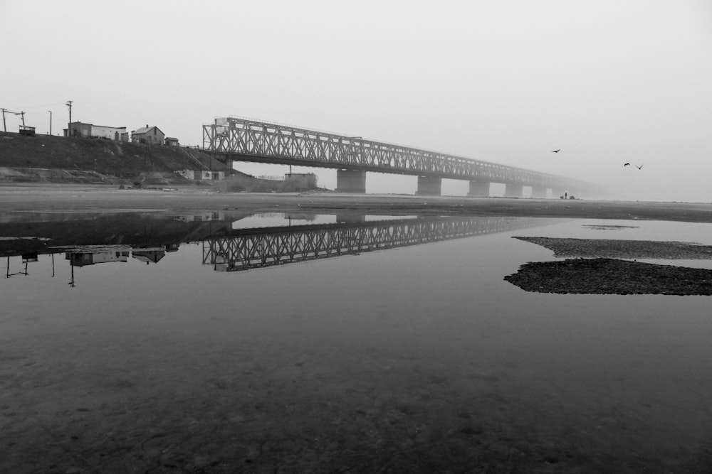 a black and white photo of a bridge over water