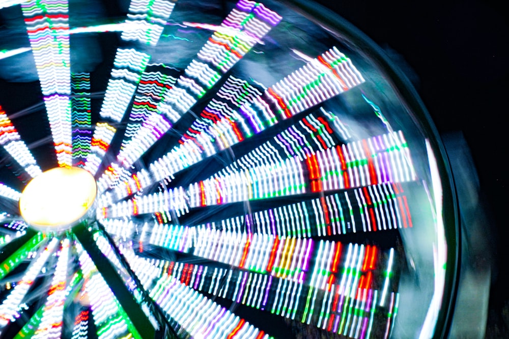 a ferris wheel spinning at night with colorful lights