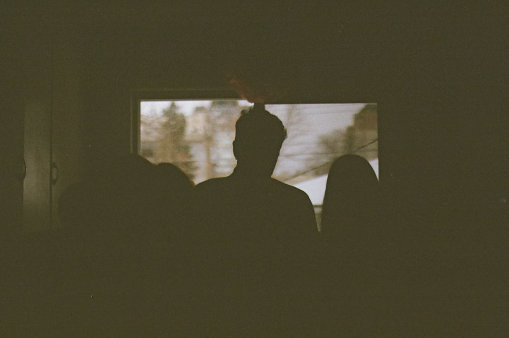 a man standing in front of a window in a dark room