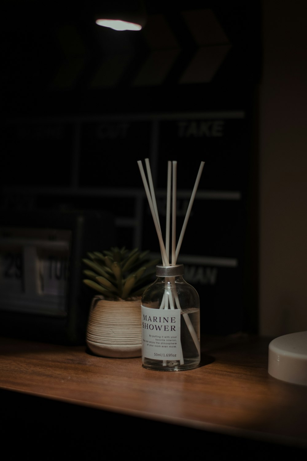 a glass bottle with a reed diffuser next to a pineapple plant