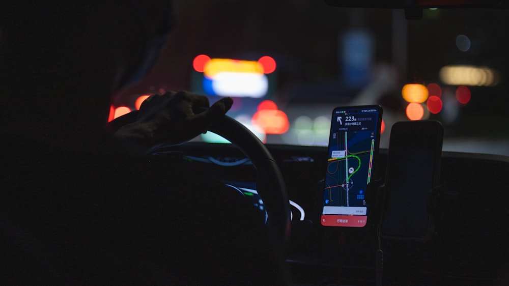 una persona que conduce un automóvil por la noche con un teléfono celular