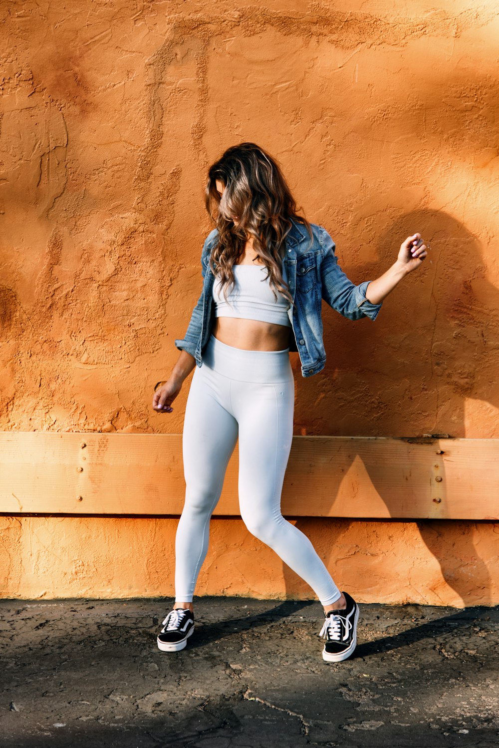 a woman in white leggings and a denim jacket