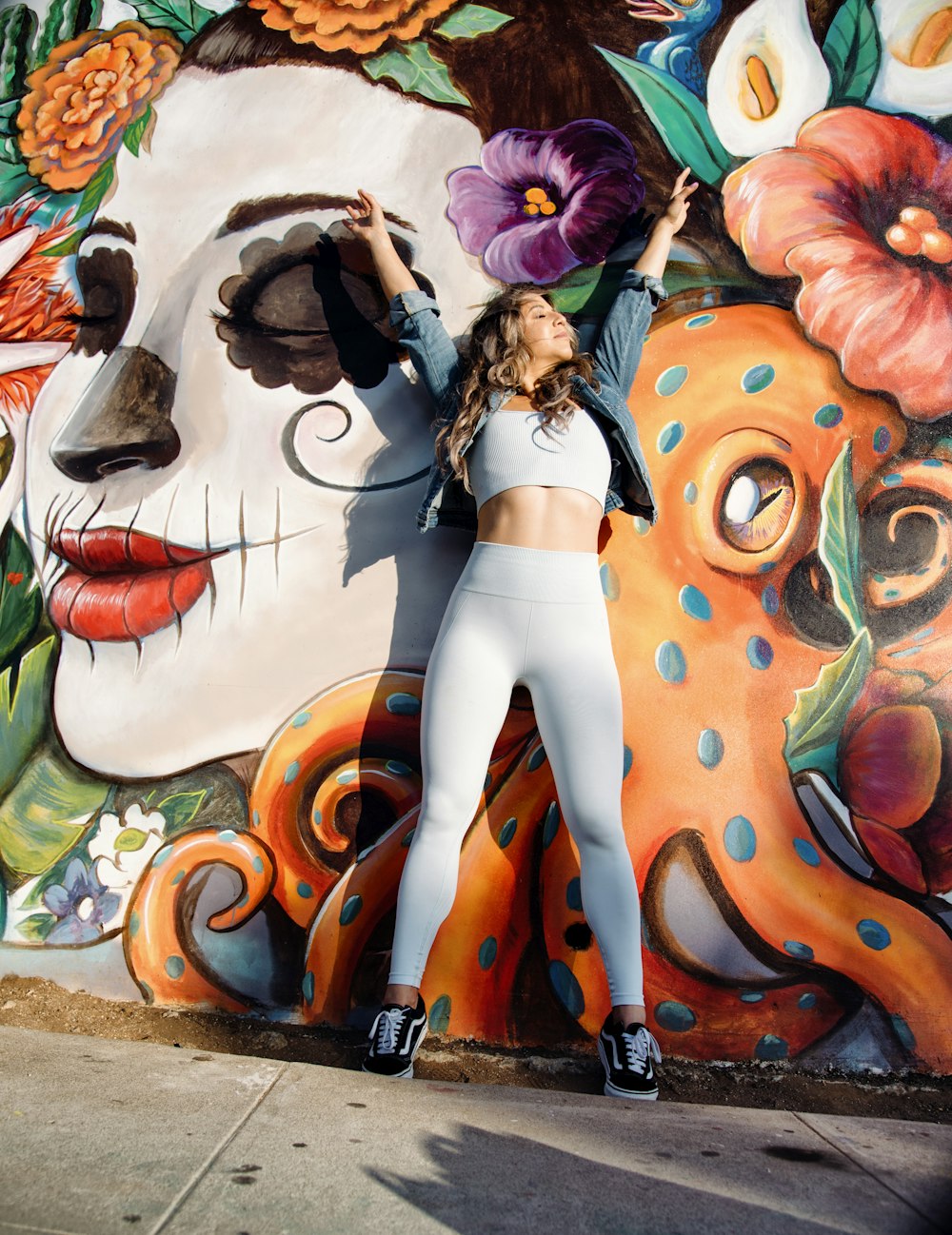 a woman is posing in front of a mural