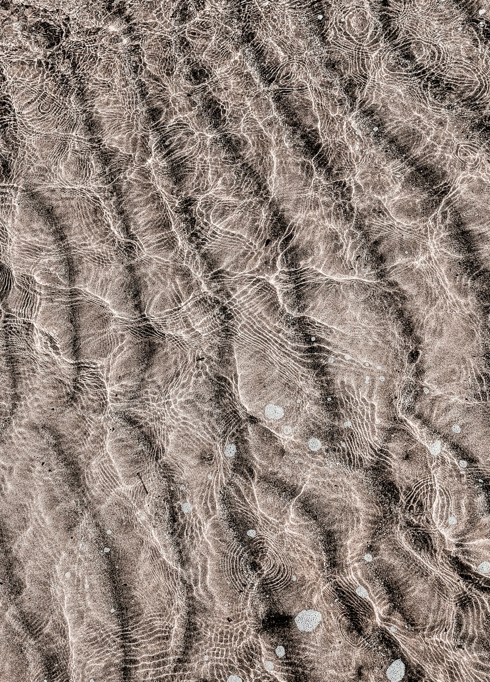 a close up of water ripples on a sandy beach