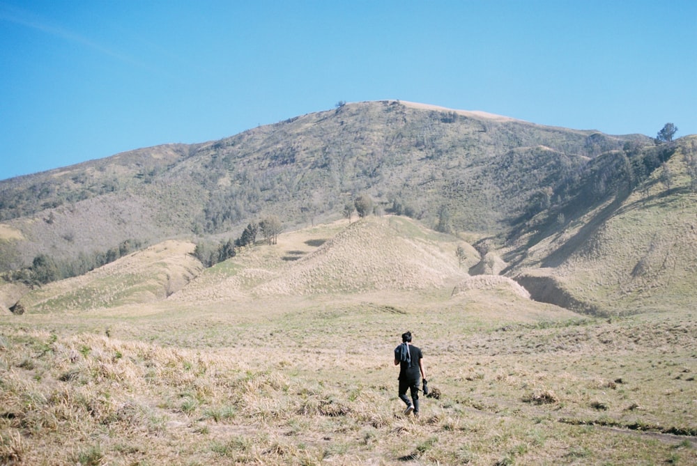 a man is standing in a field with a mountain in the background