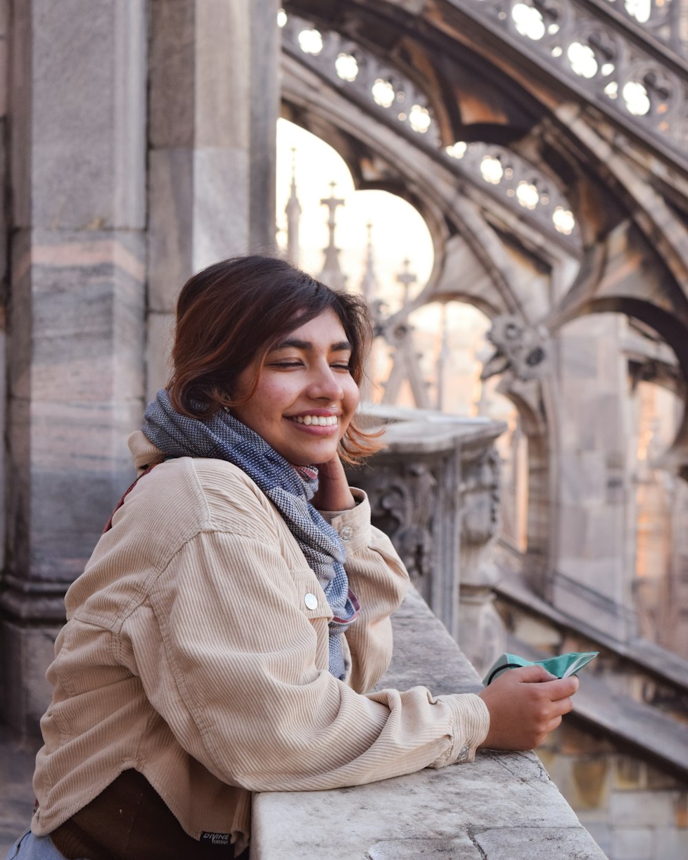 a woman leaning on a wall with a cell phone to her ear