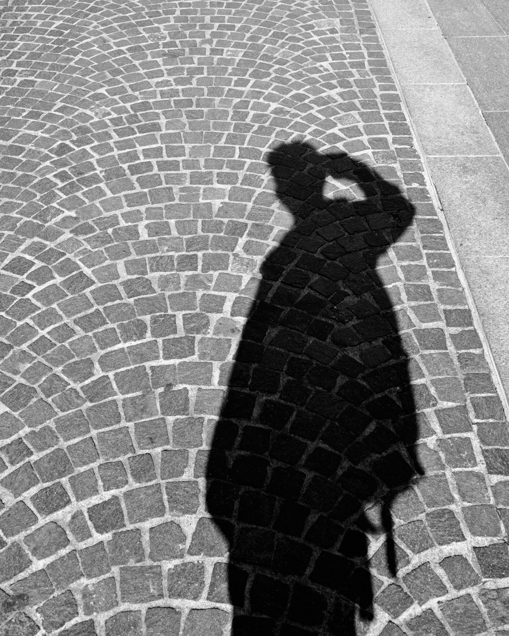 a shadow of a person on a cobblestone street