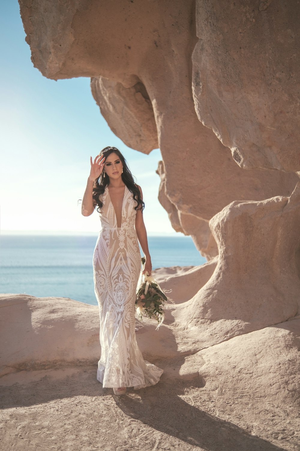 a woman in a wedding dress walking on the beach