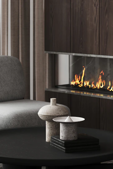 A sleek, modern luxury fireplace with a glowing flame set against a minimalist neutral-toned living room.