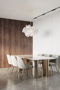 A sleek, minimalist marble dining table set in a sunlit luxury villa with gold accents.