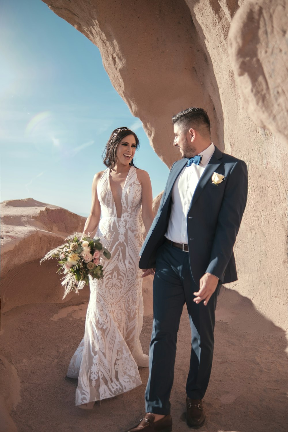 a bride and groom standing in front of a rock formation