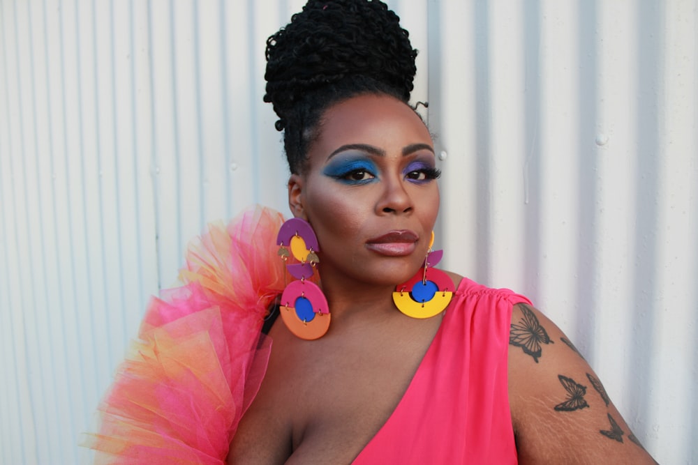 a woman in a pink dress with large statement earrings