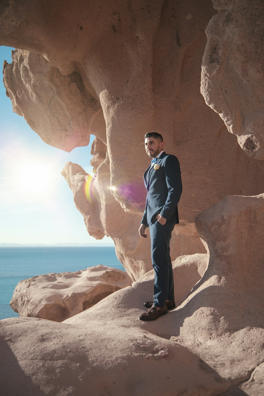 a man in a suit standing in front of a rock formation