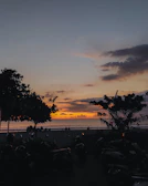 Sunset view with silhouettes of ATV riders pausing on the beach.