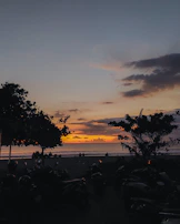 Sunset view over a beach with riders parked, sharing stories after a day’s adventure.