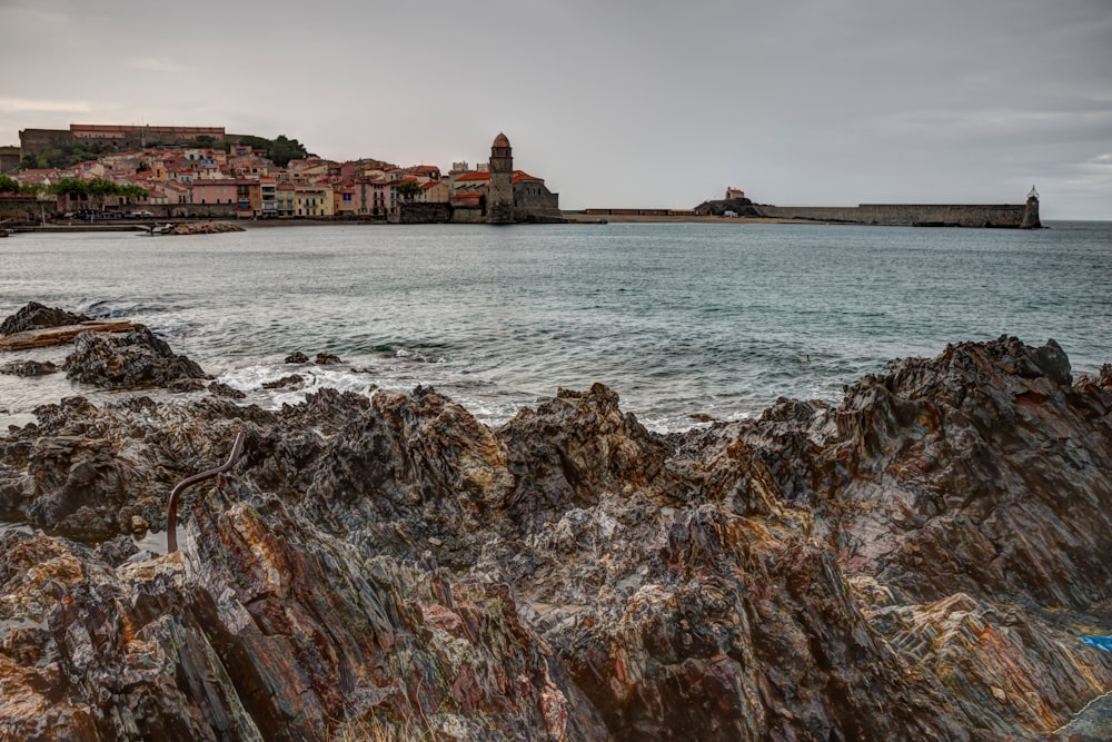 a rocky beach with buildings in the background