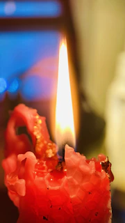 A mystical candle with intricate carvings inspired by Andean culture, glowing warmly in a dimly lit room.