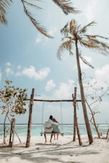 a couple sitting on a bench on a beach