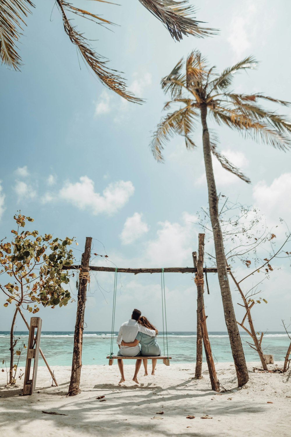 a couple sitting on a bench on a beach