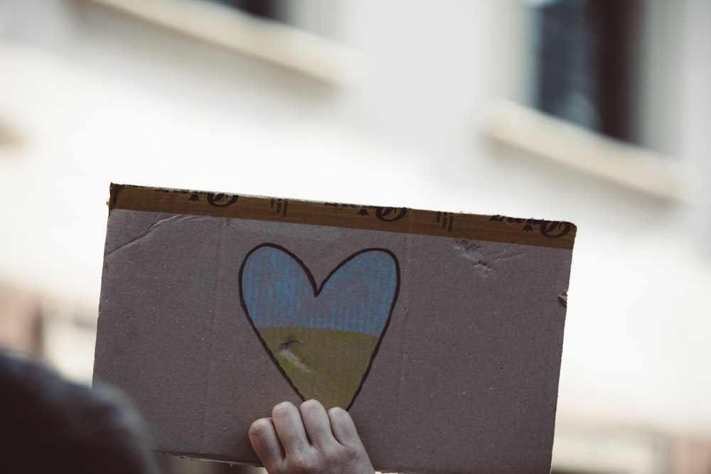 a hand holding a cardboard box with a blue and white symbol on it