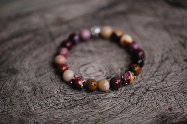 A warm, earthy-toned bracelet made from natural stones and wood beads resting on a rustic wooden table.
