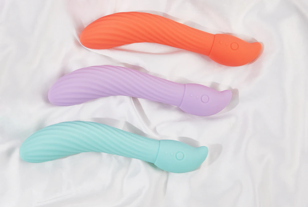 Three pastel wand massagers on white linen