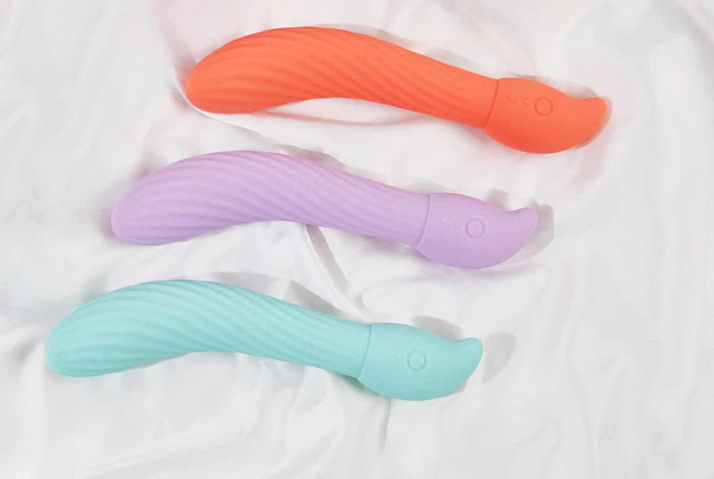 Three pastel wand massagers on white linen