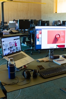 a desk with computers and a laptop