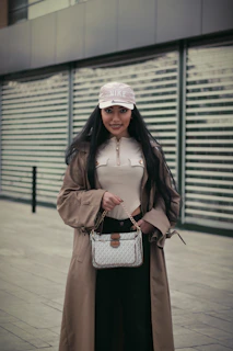 A chic street style shot featuring a model in a flowing trench coat and bold accessories against an urban backdrop.