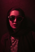 A sophisticated model wearing sculpted eyewear and a timeless scarf in soft natural light.