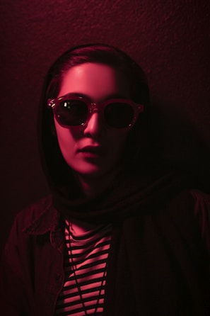 A sophisticated model wearing sculpted eyewear and a timeless scarf in soft natural light.