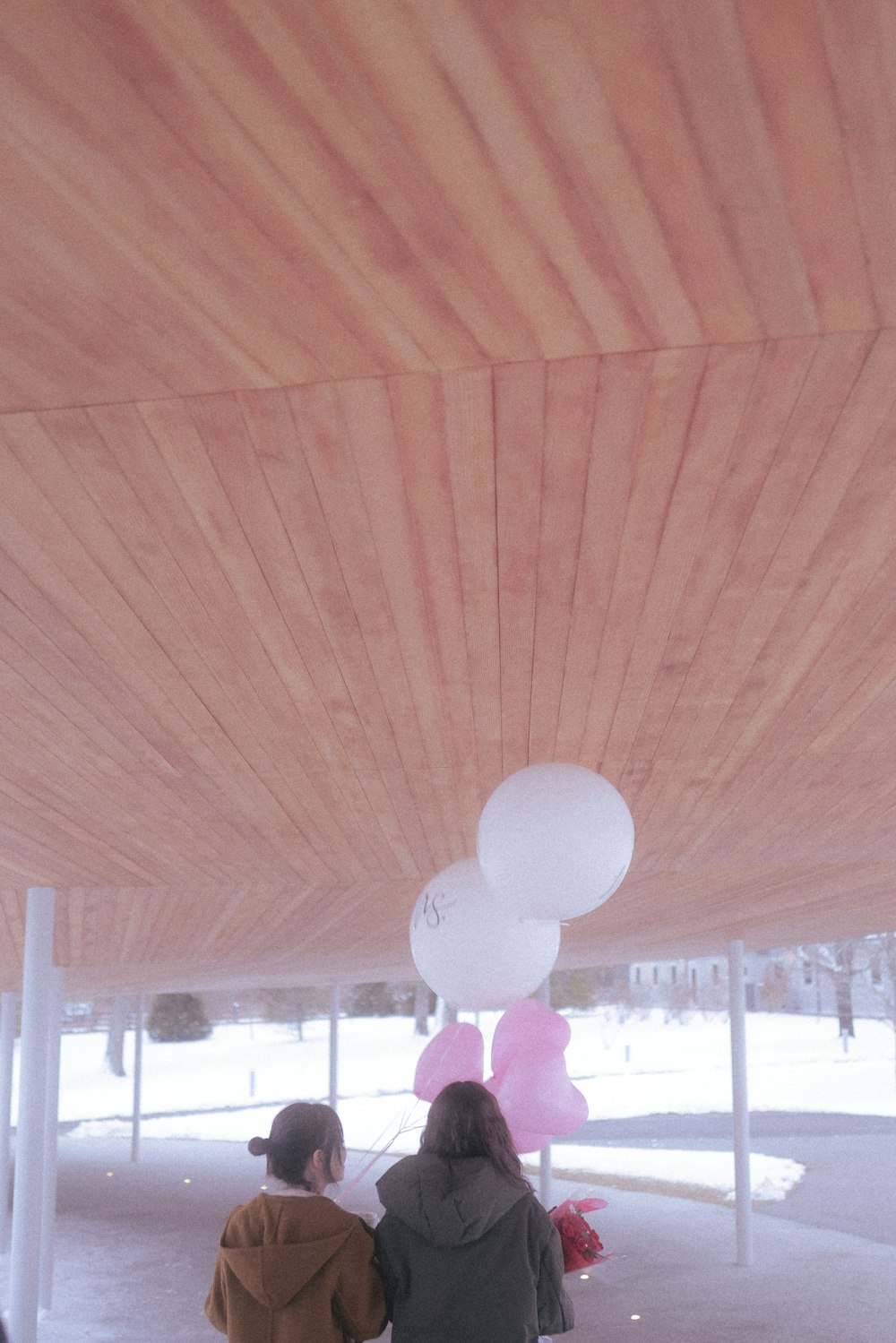 a group of people sitting under a tent with white balloons