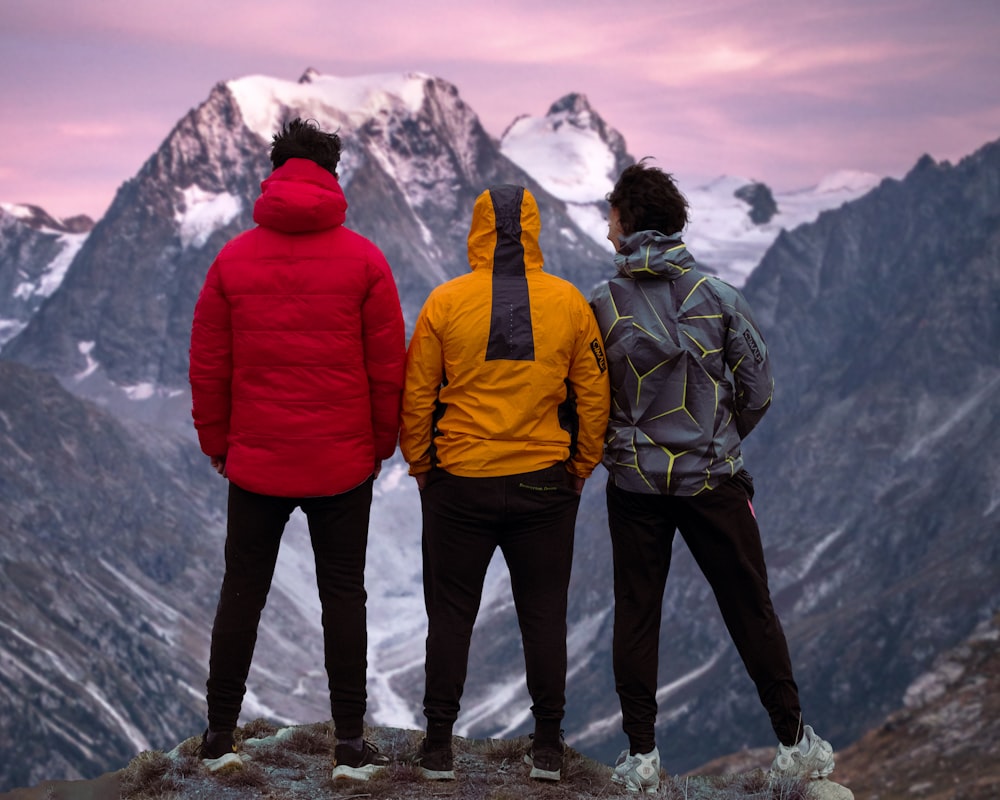 a group of people standing on a mountain top looking at the mountains