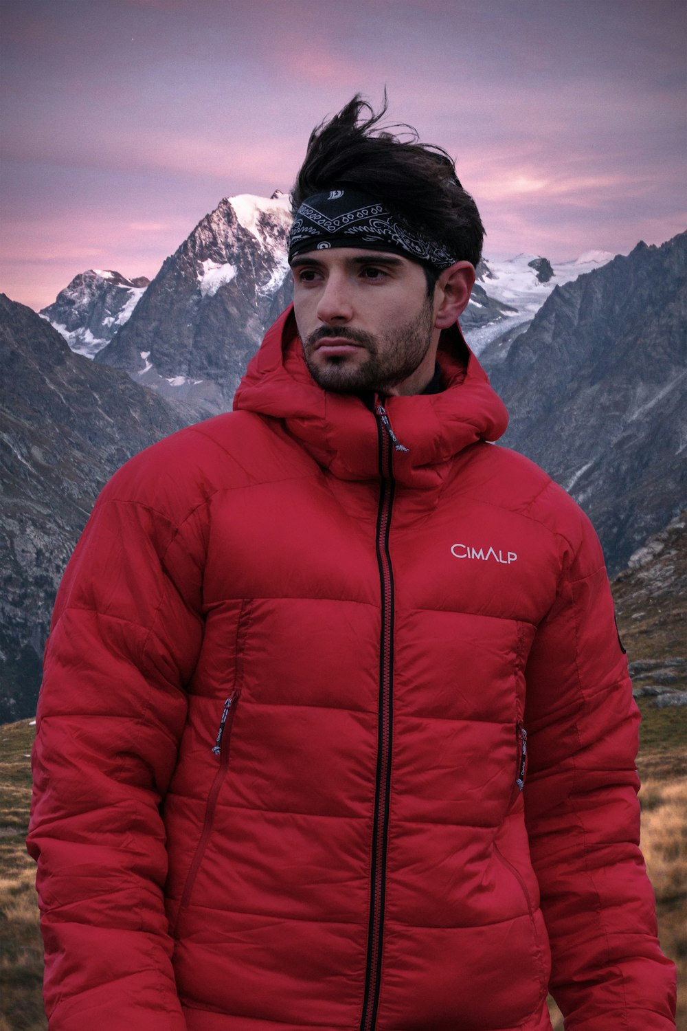 a man wearing a red coat and hat with a mountain in the background