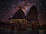 A serene Bhutanese temple silhouetted against a vast star-filled midnight blue sky.