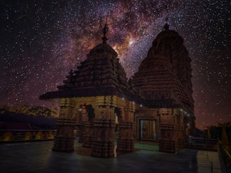 A serene night sky filled with stars and planets aligning over an ancient Vedic temple.