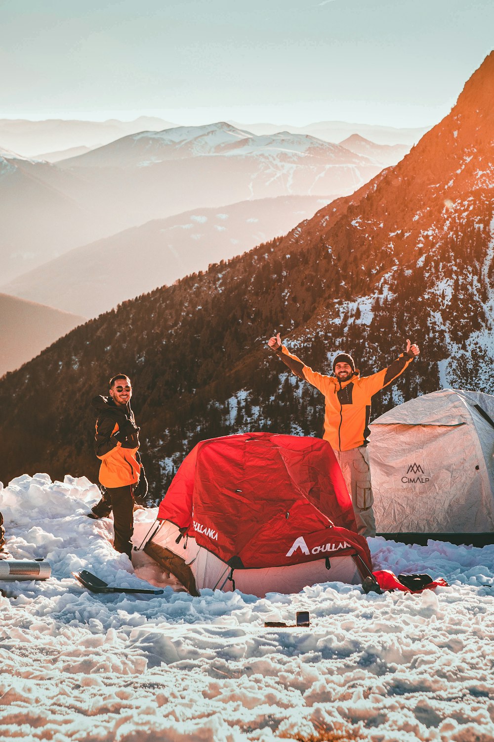 um grupo de pessoas em pé em torno de uma tenda na neve