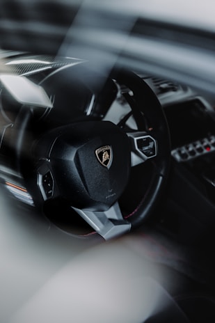 Close-up of a stylish steering wheel with orange accents inside a luxury car, emphasizing detail and elegance.