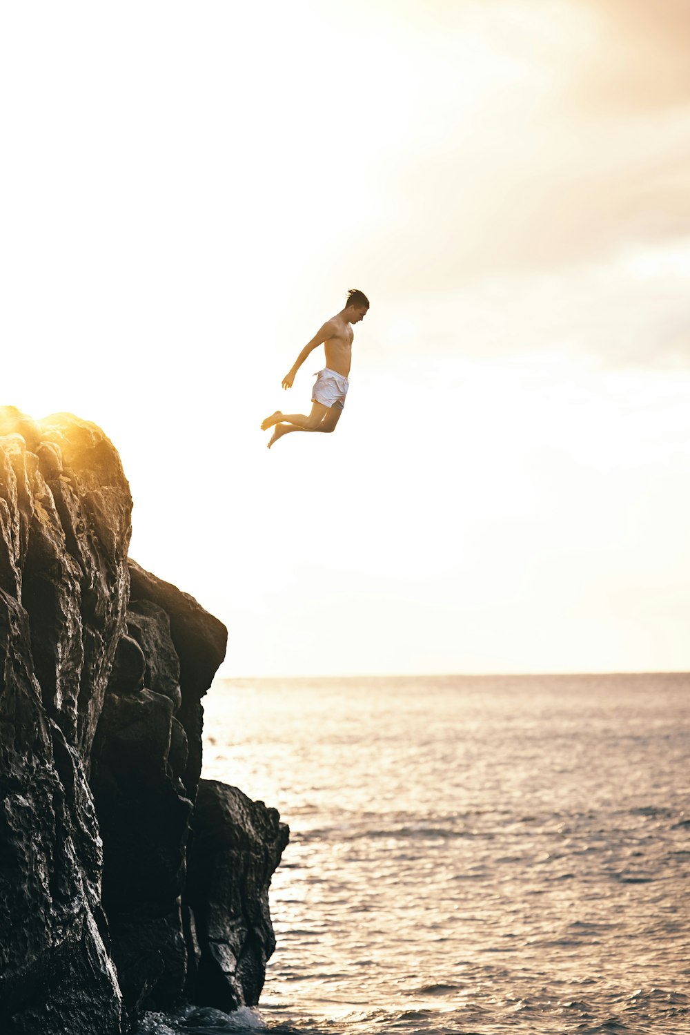 a man jumping off a cliff into the water