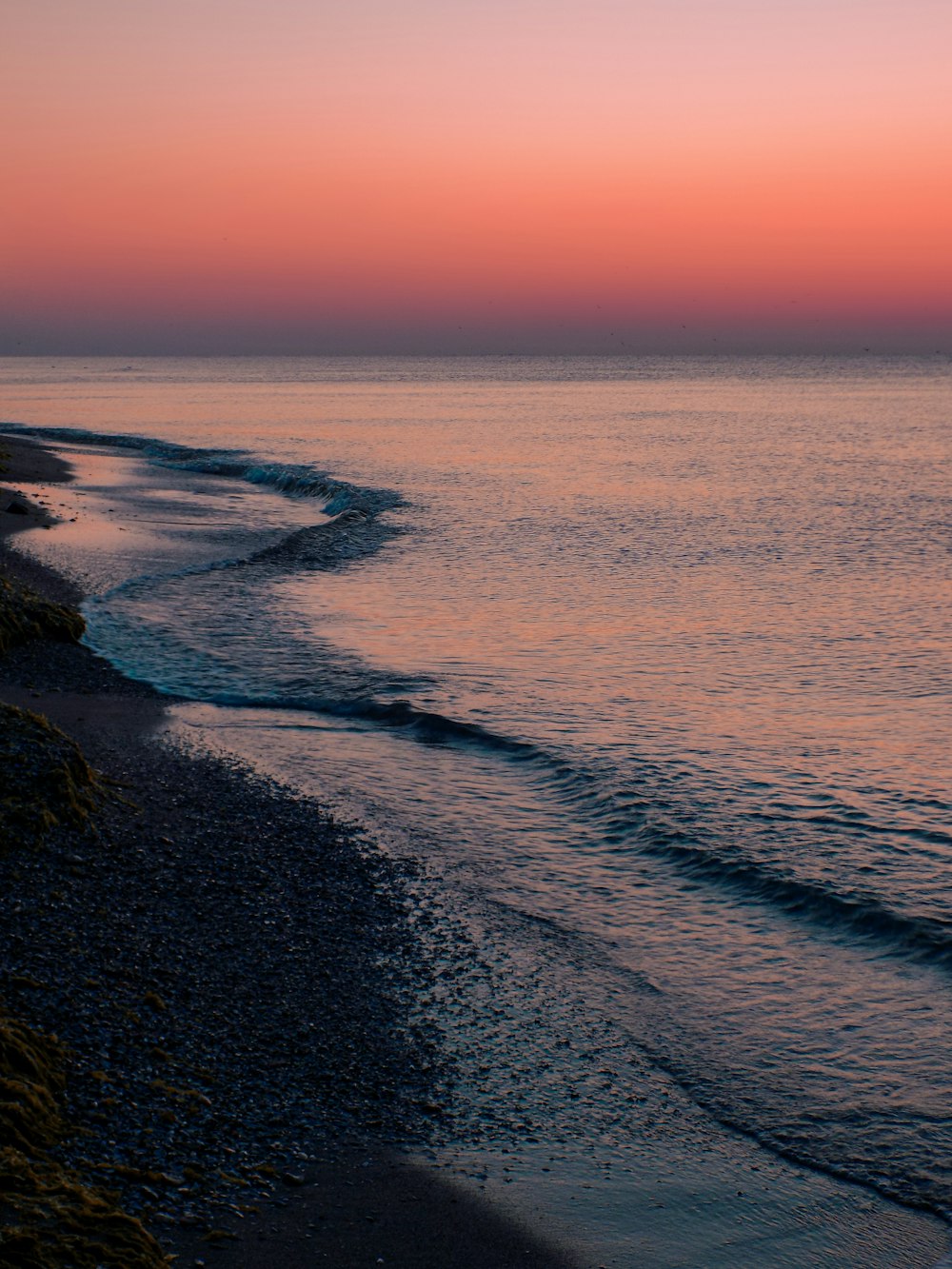 a beach with a pink and purple sunset